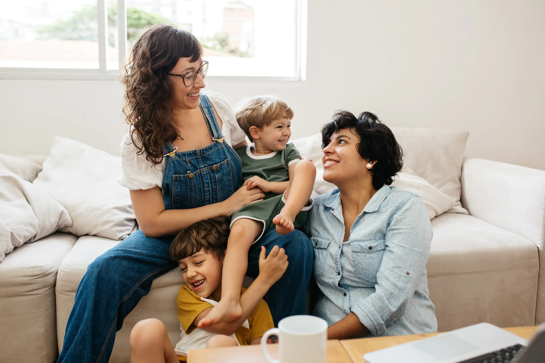 Happy lesbian couple playing with their children at home. Beautiful family of four having great time together indoors- Alternative Insemination, Artificial Insemination, AI, AI Program