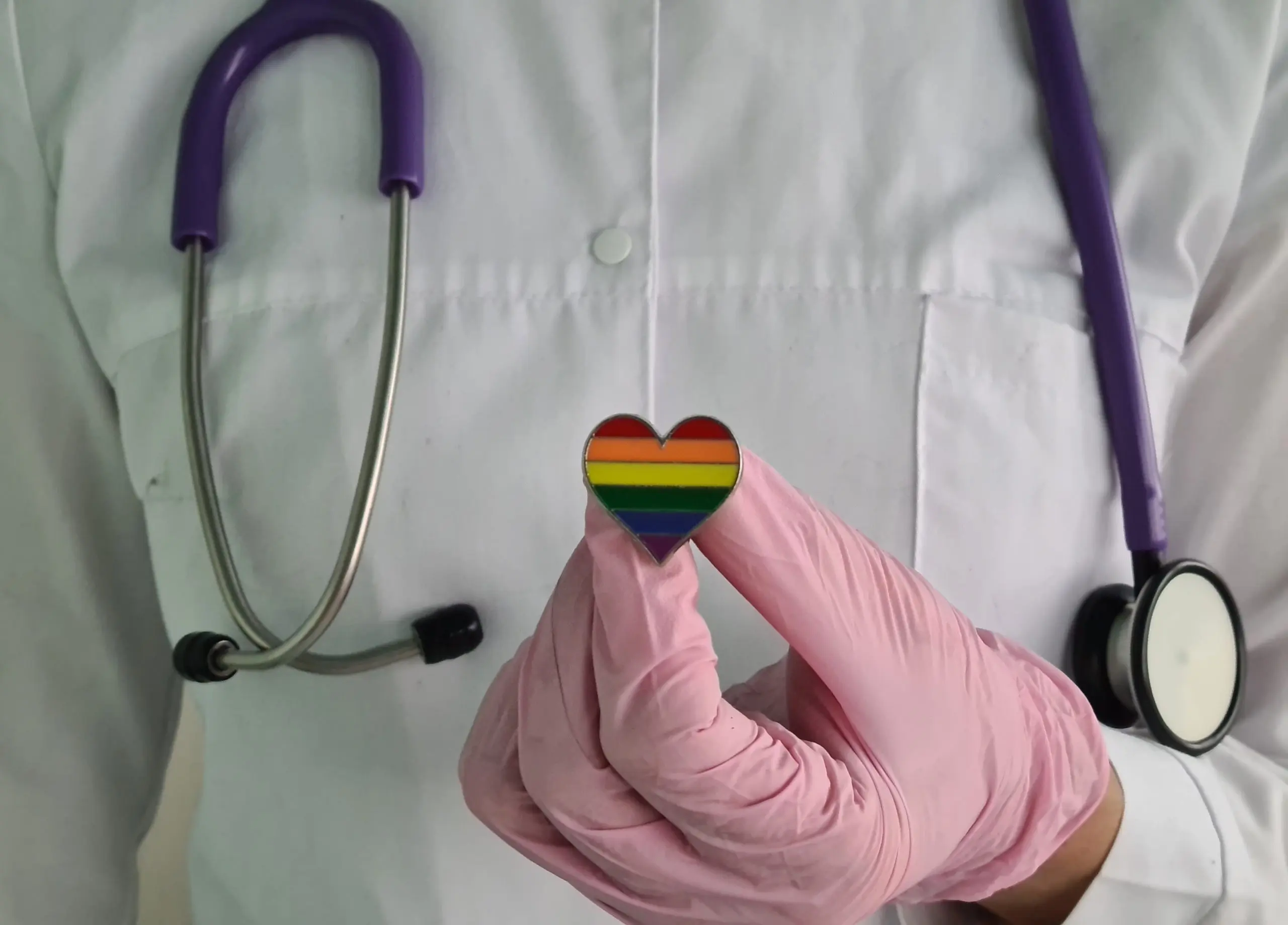 Woman doctor with lgbt heart flag in hand in clinic. Medical assistance to support the LGBT community and transgender people