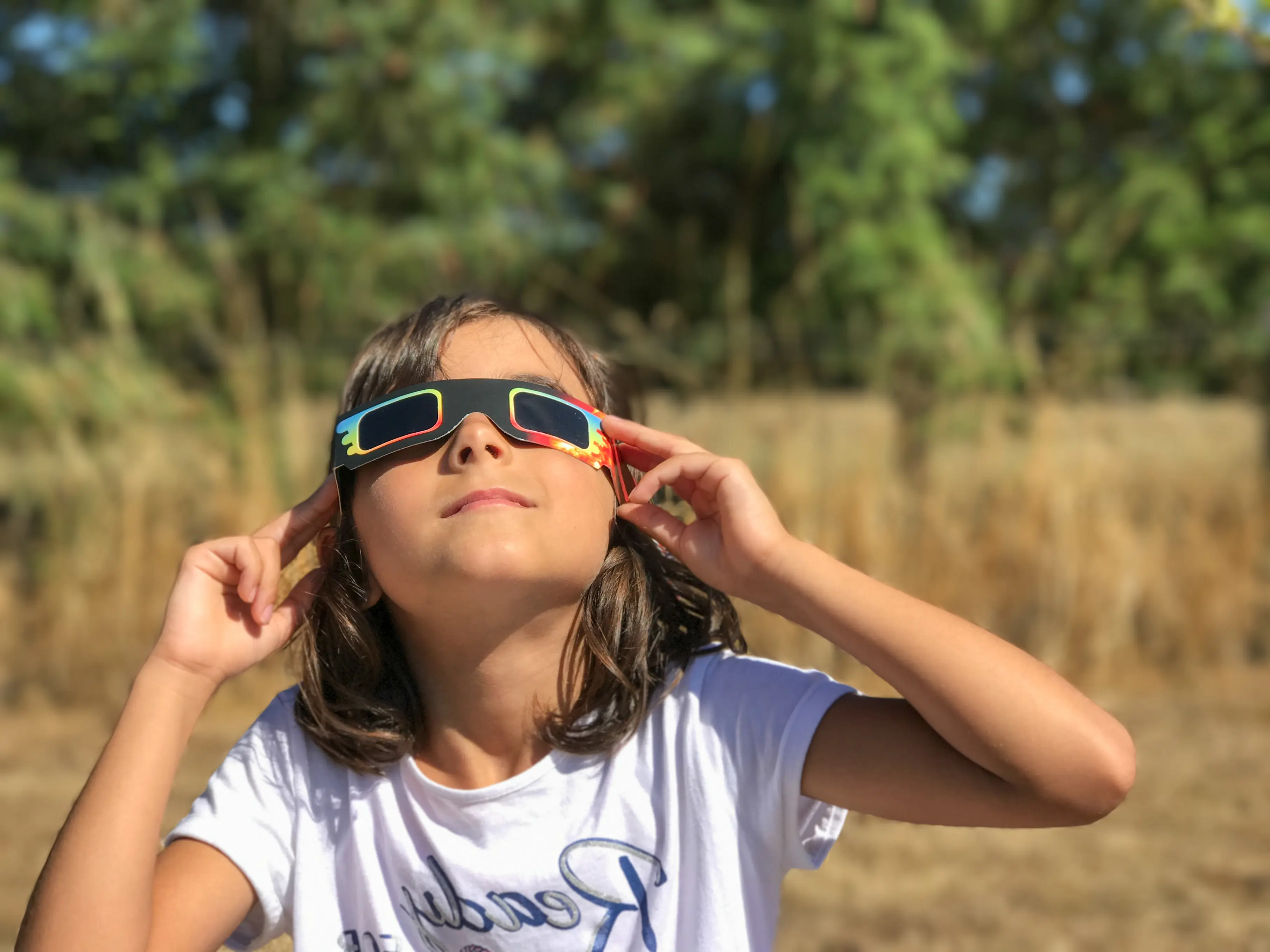 A young person watching an eclipse using eclipse safety glasses