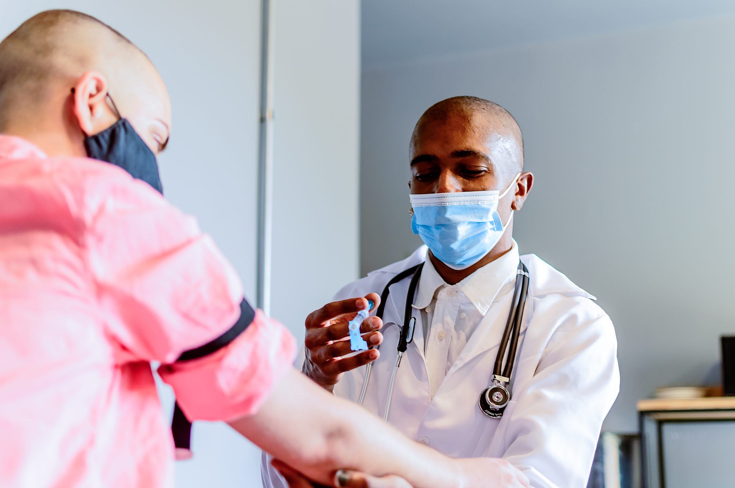 A black doctor giving a vaccine to a non-binary young